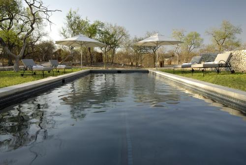 a pool of water with chairs and umbrellas at The Mushara Outpost in Namutoni