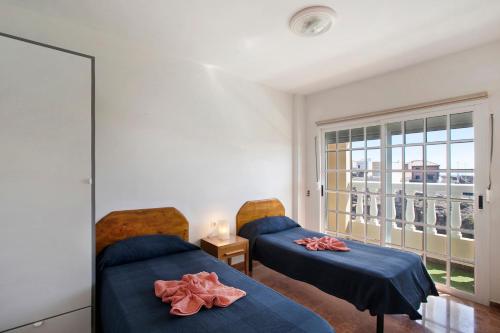 una camera con due letti con lenzuola blu e una finestra di Casa del Pescador planta alta a Las Eras