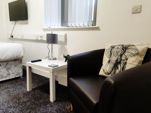 Habitación con sofá y mesa con silla. en Accommodation Bradford, en Bradford