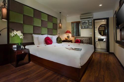 a large bedroom with a large white bed with red pillows at Ambassador Hanoi Hotel & Spa in Hanoi