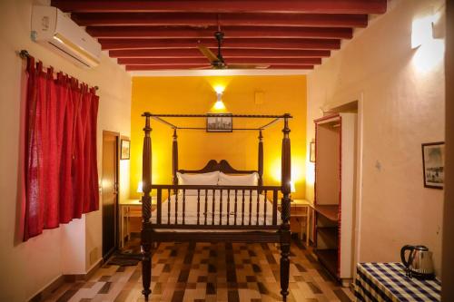 Cama en habitación con cortina roja en The French Villa, en Pondicherry
