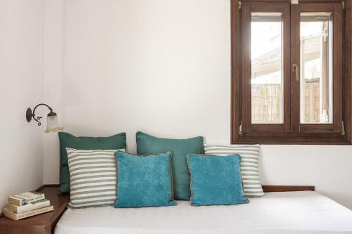 a bed with blue and white pillows and a window at Mani Tower by Olive Villa Rentals in Oítilon
