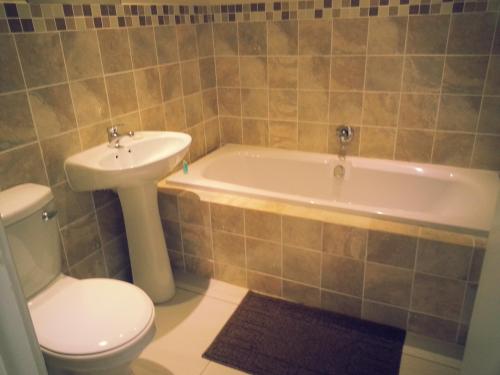a bathroom with a toilet and a tub and a sink at The Homestead Margate - South Africa in Margate