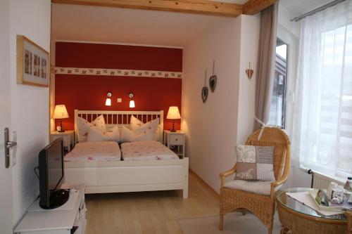 a bedroom with a white bed and a chair at Schönes Doppelzimmer mit separater Küche im nördlichen Nationalpark Schwarzwald in Forbach