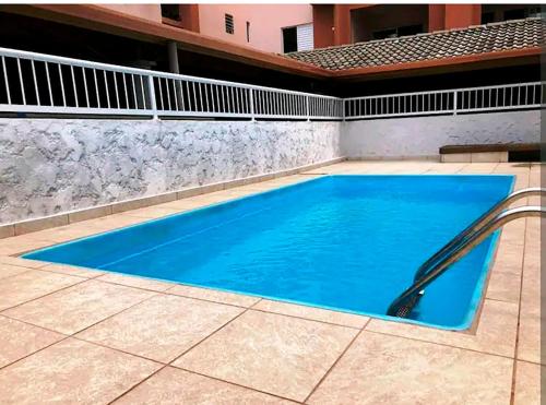 ein Pool in einem Haus mit blauem Wasser in der Unterkunft Incrível Apto com piscina e churrasq em Ubatuba SP in Ubatuba