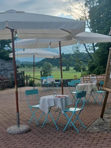 a group of tables and chairs under a white umbrella at Open Cascina in Colico