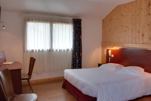 a hotel room with a large bed and a window at Le Chalet de la Foret Logis Hôtel 3 étoiles et restaurant in Vierzon