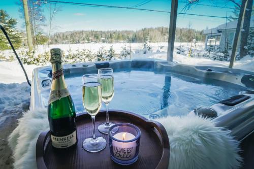a bottle of champagne and two glasses on a table with a hot tub at Chalet Le Convivial Tremblant in Lac-Superieur