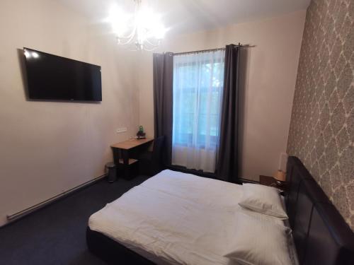 a bedroom with a bed and a flat screen tv at Hotel Kārklu Muiža in Jelgava