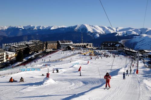 a group of people skiing down a snow covered slope at Résidence Odalys Soleil d'Aure in Saint-Lary-Soulan