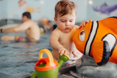 a baby playing with a toy in a swimming pool at Familienhotel Huber in Valles