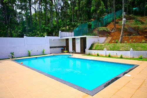 a large blue swimming pool in front of a house at Besrauma Vythiri in Vythiri