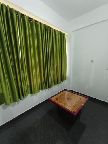 a room with green curtains and a wooden table at Besrauma Vythiri in Vythiri