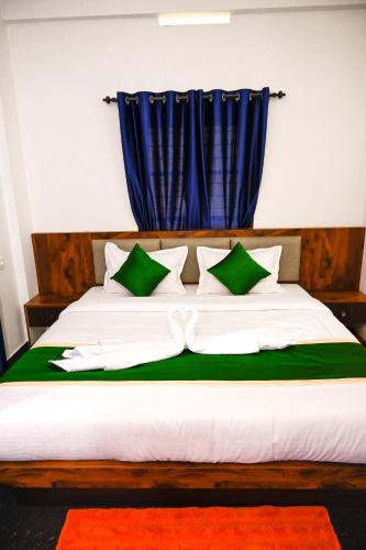 a bed with green and white pillows and a blue curtain at Besrauma Vythiri in Vythiri