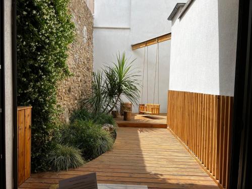 a wooden walkway in a courtyard with plants at Lily l'Acrobate Aubagne-Cassis-Aix en Provence in Aubagne