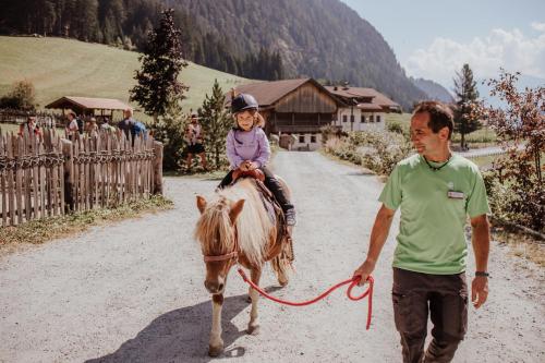 a man leading a little girl on a pony at Familienhotel Huber in Valles