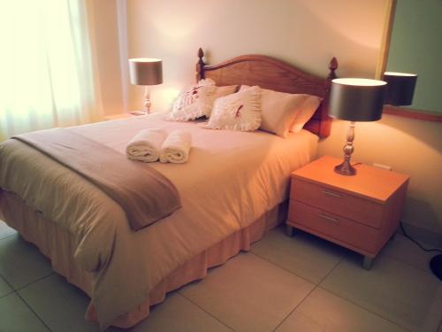 a bedroom with a bed with towels on it at The Homestead Margate - South Africa in Margate