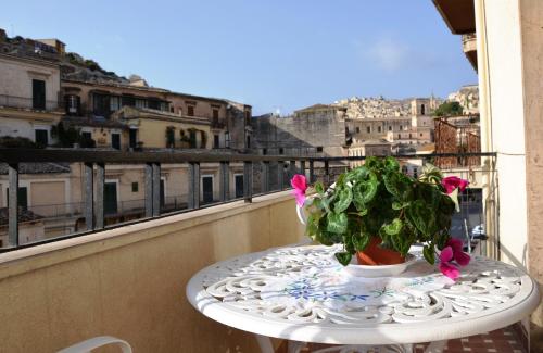 a table with a potted plant on a balcony at Stanze Barocche in Modica