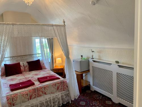 a bedroom with a canopy bed with red pillows at Knighton Lodge in Skegness