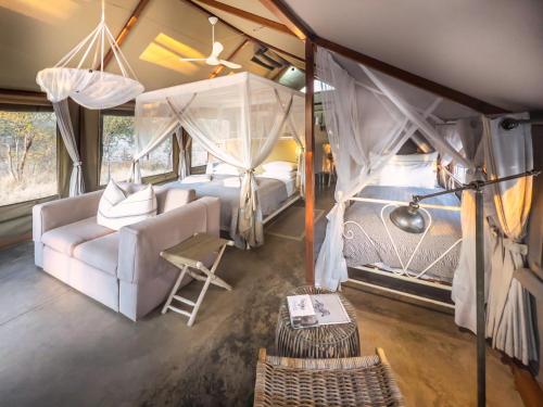 a bedroom with a bed and a couch in a tent at Mushara Bush Camp in Namutoni