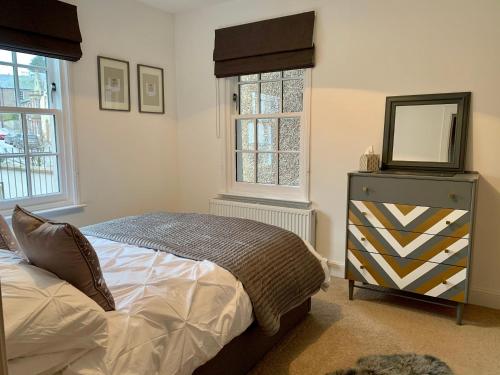 a bedroom with a bed and a mirror and windows at Monboddo Townhouse in Auchenblae