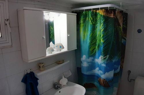 a bathroom with a sink and a tropical shower curtain at KLEO HOUSE Kalives Polygyros Halkidiki in Kalives Poligirou