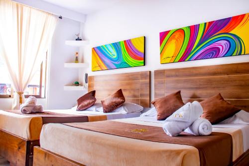 2 camas en una habitación con pinturas en la pared en Hotel Plaza Real, en Santa Rosa de Cabal