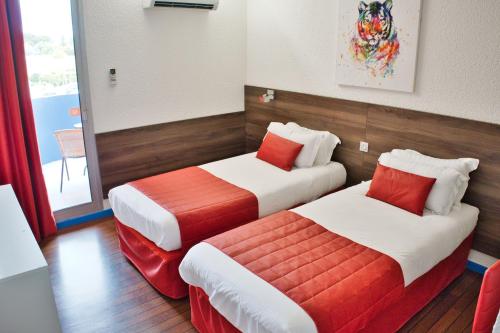 a room with two beds with red and white at Cit'Hotel des 2 Golfs in Port Leucate