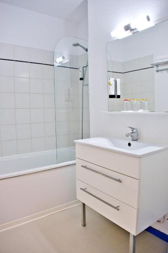 a white bathroom with a sink and a mirror at Cit'Hotel des 2 Golfs in Port Leucate