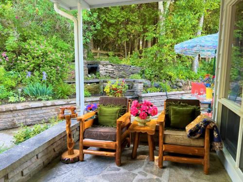 a porch with two chairs and a table with flowers on it at Somewhere In Time - RETRO SPACIOUS COTTAGE with PRIVATE SANDY BEACH in Wiarton