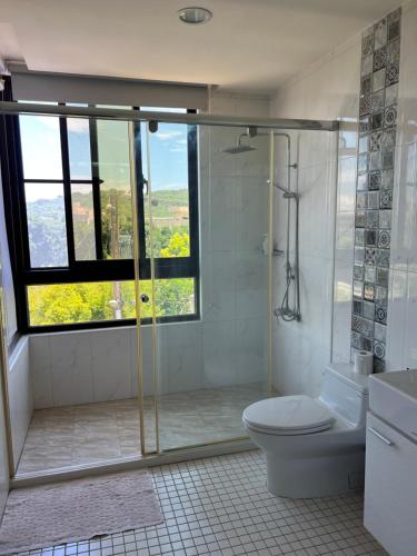 ein Bad mit einer Dusche, einem WC und einem Fenster in der Unterkunft el Bulli Inn in Hualien