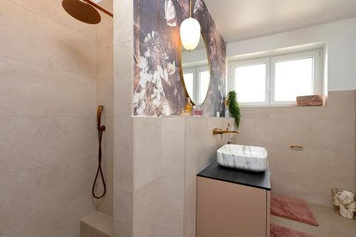 a bathroom with a sink and a shower with a mirror at S design apartment in Zadar