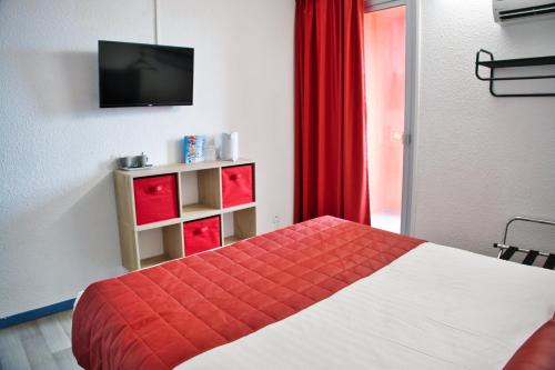 a bedroom with a bed and a tv and red curtains at Cit'Hotel des 2 Golfs in Port Leucate