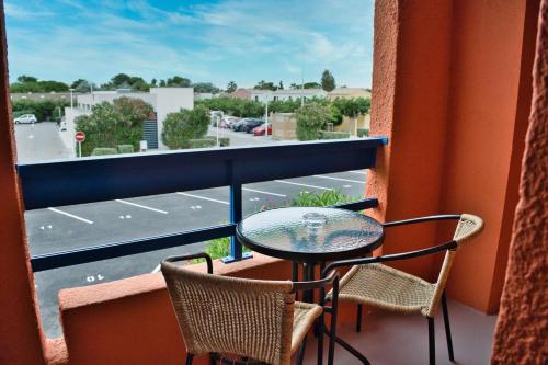 a balcony with a table and chairs and a view of a parking lot at Cit'Hotel des 2 Golfs in Port Leucate