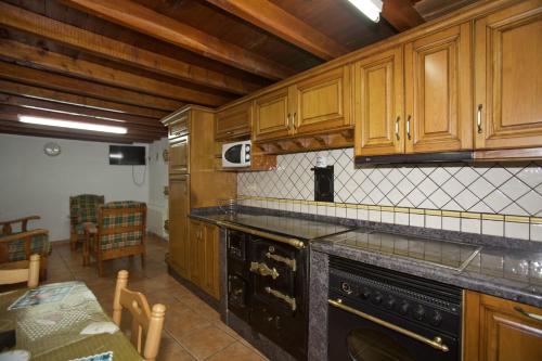 La cuisine est équipée de placards en bois et d'une cuisinière noire. dans l'établissement Casa Criseva II, à Avín