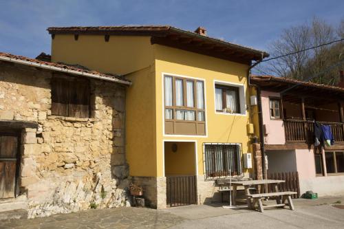 ein gelbes Haus mit einem Picknicktisch davor in der Unterkunft Casa Criseva II in Avín