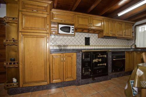 - une cuisine avec des placards en bois et un four micro-ondes dans l'établissement Casa Criseva II, à Avín
