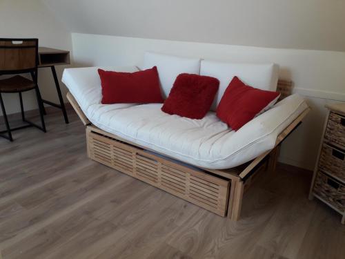 eine Couch mit drei roten Kissen auf einem Zimmer in der Unterkunft Lodge avec SPA pour 6 pers, proche de Guédelon in Tannerre-en-Puisaye