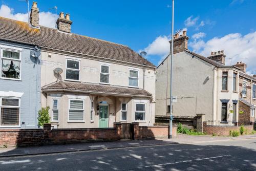 a white house with a green door on a street at Guest Homes - The Haven at Church Road in Gorleston-on-Sea