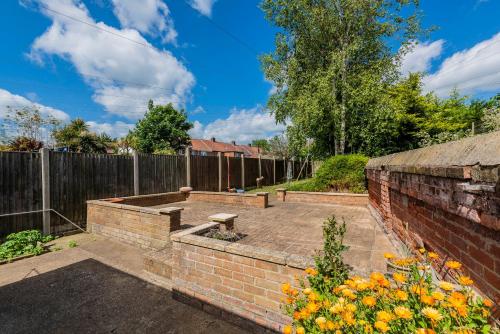 a garden with a brick wall and a fence at Guest Homes - The Haven at Church Road in Gorleston-on-Sea