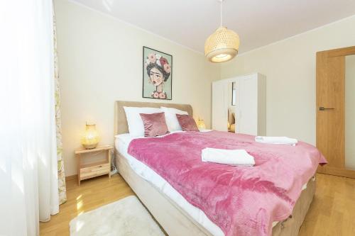 sypialnia z dużym łóżkiem i różowym kocem w obiekcie Pomorskie Apartamenty Bernadowska Green Deluxe w mieście Gdynia