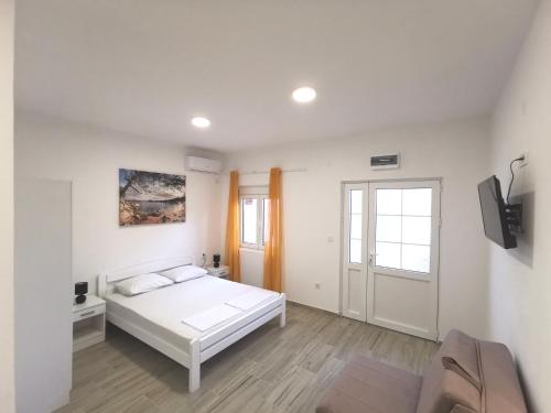 a white bedroom with a bed and a tv at Dorija in Zmijice