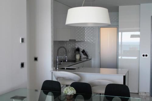 a kitchen with a glass table with chairs and a sink at Sunset Drive nice komplex on the beach Poniente in Benidorm