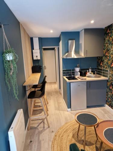 Una pequeña cocina con paredes azules y mesas y sillas. en Studio Eden Jacuzzi, en Amiens