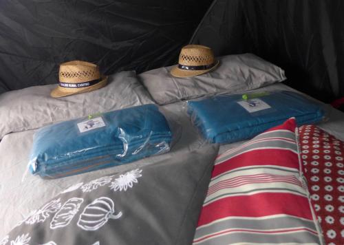 a bed with two pillows and two hats on it at Capalbio Campeggio Rurale in Capalbio