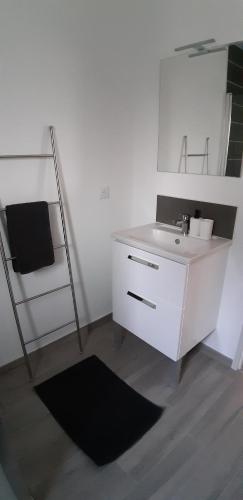 uma casa de banho branca com um lavatório e um espelho em Le 66 bis - maison neuve em Saint-Martin-la-Rivière