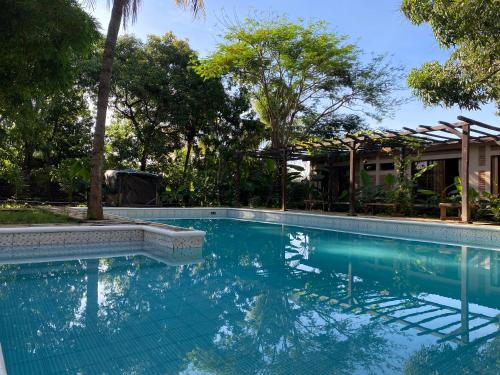 a swimming pool in front of a house with trees at Hostal Casa Abierta in León