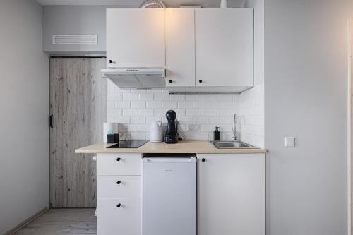 a white kitchen with white cabinets and a sink at Narutowicza I by LookAp in Łódź