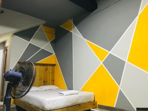 1 dormitorio con una pared amarilla y gris y ventilador en Alina Budget Hotel, en Kaduwela