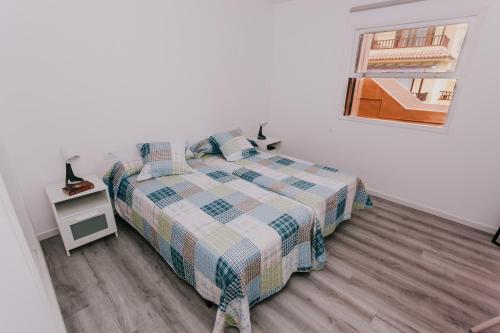um quarto com uma cama com um edredão xadrez em Alma 28 em Los Cancajos